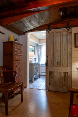 A rustic interior with a wooden chair, a wooden cabinet, and a door leading to another room.