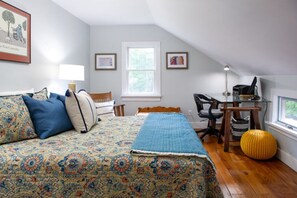 A bedroom with a bed, a desk, a chair, a lamp, and a window.