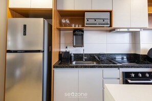 Eine moderne Küche mit einem Edelstahl-Kühlschrank, einem eingebauten Backofen und einem Gasherd.