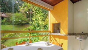 Een kamer met een gedekte tafel voor thee, een raam met uitzicht op een tuin en een klein wastafeltje.