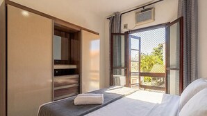 A bedroom with a bed, a wardrobe, and a window with a view. - Apart w/ Balcony in Condominium With Pool Vdp0000 (Cabo Frio)