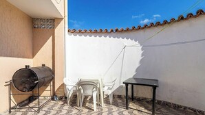 A patio with a barbecue grill, a table, and chairs. - Apart w/ Balcony in Condominium With Pool Vdp0000 (Cabo Frio)