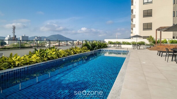 Une piscine sur le toit, dotée d’un sol carrelé, entourée de verdure et de mobilier d’extérieur.