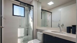 Une salle de bain moderne avec une douche à parois de verre, des toilettes, un lavabo avec un miroir et une fenêtre.