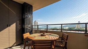 Un balcon avec une table ronde et des chaises, une vue sur le paysage urbain et un bâtiment doté d’une façade à lattes.