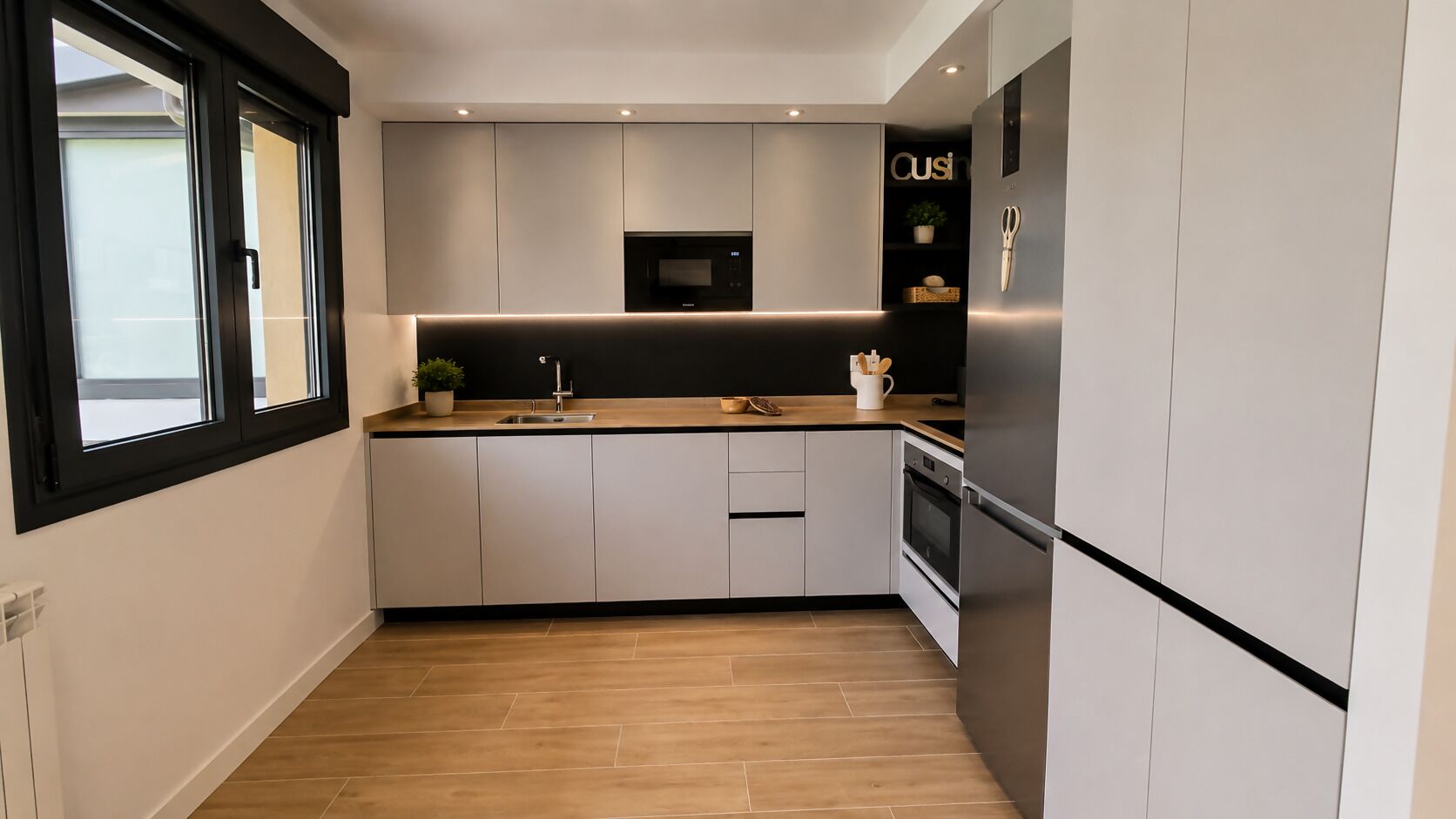 A modern kitchen with a built-in oven, a microwave, and a refrigerator.