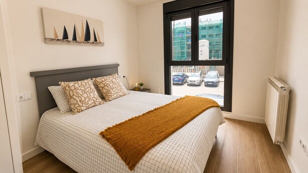 A bedroom with a bed, a window with a view of parked cars, a radiator, and a wall-mounted artwork. - Villa Carinn Sella - Ribadesella - Beach 2 km away (Ribadesella)