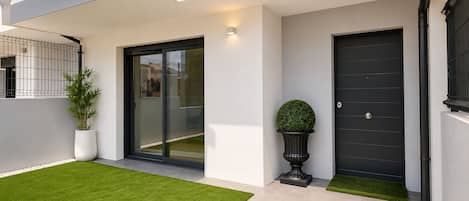 A modern entrance with a sliding glass door, a black door, and a potted plant.