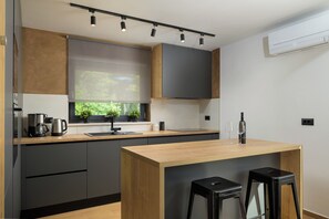 A modern kitchen with a wooden countertop, a coffee maker, a sink, and a window with plants. - Villa Mochi (Istria - Pićan) (Pićan)