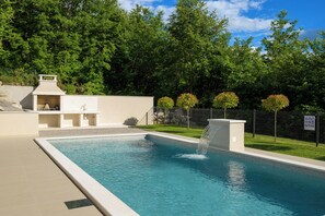 A rectangular swimming pool with a waterfall feature, surrounded by a fence and trees. - Villa Mochi (Istria - Pićan) (Pićan)