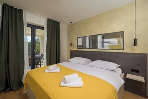 Une chambre d’hôtel avec un lit, une grande fenêtre avec des rideaux, un tableau au mur et une vue sur l’extérieur.
