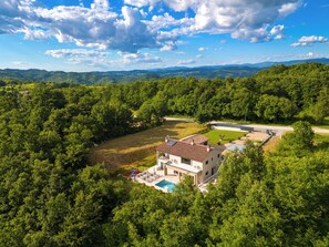 A house with a swimming pool, surrounded by dense greenery and hills in the background. - Villa Mochi (Istria - Pićan) (Pićan)