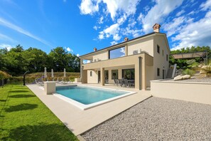 Une maison moderne à deux étages dotée d’une piscine, d’un espace salon extérieur et d’un patio couvert.