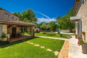 A courtyard with a stone building, a covered patio, and a well-maintained lawn. - Villa Roveria (Istria - Butkovići) (Butkovići)