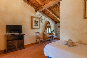 A bedroom with a wooden ceiling, a bed with white bedding, a television on a wooden cabinet, a desk with a mirror, and a framed picture on the wall. - Villa Roveria (Istria - Butkovići) (Butkovići)