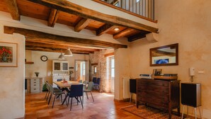 A spacious dining area with a wooden table and chairs, a kitchen in the background, and a stone wall. - Villa Roveria (Istria - Butkovići) (Butkovići)