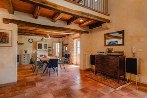 A spacious dining area with a wooden table and chairs, a kitchen in the background, and a stone wall. - Villa Roveria (Istria - Butkovići) (Butkovići)