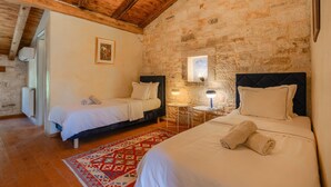 A room with two beds, a stone wall, a wooden ceiling, and a small window. - Villa Roveria (Istria - Butkovići) (Butkovići)