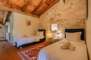 A room with two beds, a stone wall, a wooden ceiling, and a small window. - Villa Roveria (Istria - Butkovići) (Butkovići)