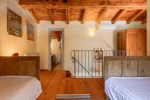 A room with wooden beams on the ceiling, a bed, a wardrobe, and a staircase leading to another room. - Villa Roveria (Istria - Butkovići) (Butkovići)