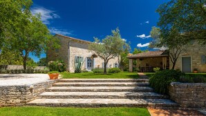 A stone building with a covered outdoor seating area, a well-maintained lawn, and a clear sky. - Villa Roveria (Istria - Butkovići) (Butkovići)