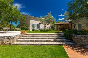 A stone building with a covered outdoor seating area, a well-maintained lawn, and a clear sky. - Villa Roveria (Istria - Butkovići) (Butkovići)