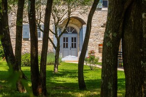 A stone building with a central arched doorway, surrounded by trees and a well-maintained lawn. - Villa Roveria (Istria - Butkovići) (Butkovići)