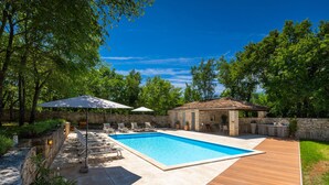 A swimming pool with lounge chairs and umbrellas, surrounded by a stone wall and greenery. - Villa Roveria (Istria - Butkovići) (Butkovići)