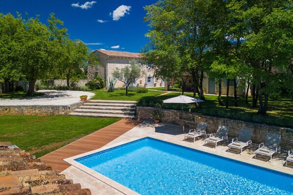 A swimming pool with lounge chairs and a stone building in the background. - Villa Roveria (Istria - Butkovići) (Butkovići)