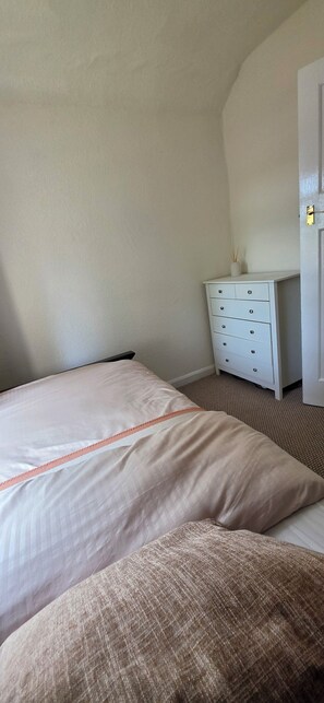 Un dormitorio con una cama, una mesita de noche y una puerta.