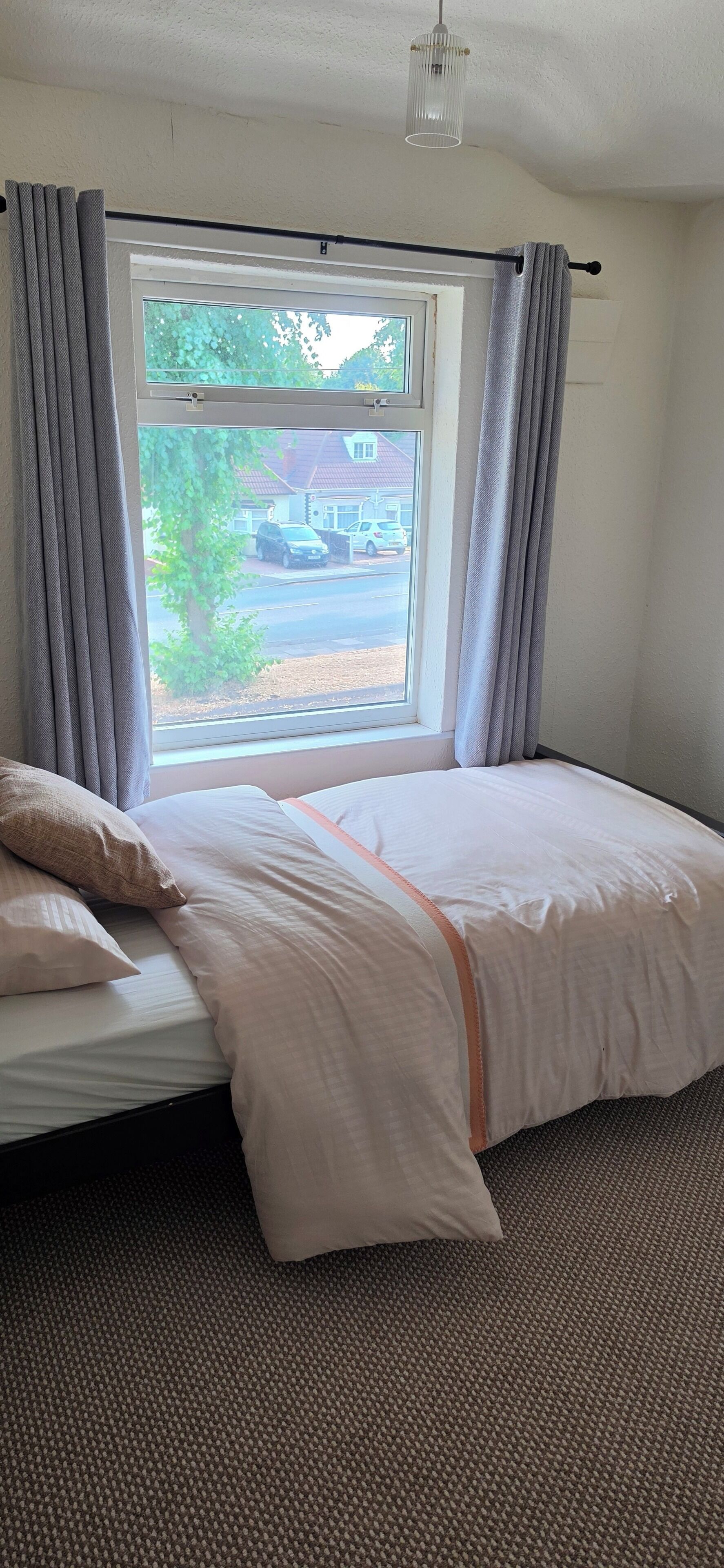 Ein Schlafzimmer mit einem Bett, Vorhängen, einem Fenster und einem Teppich.