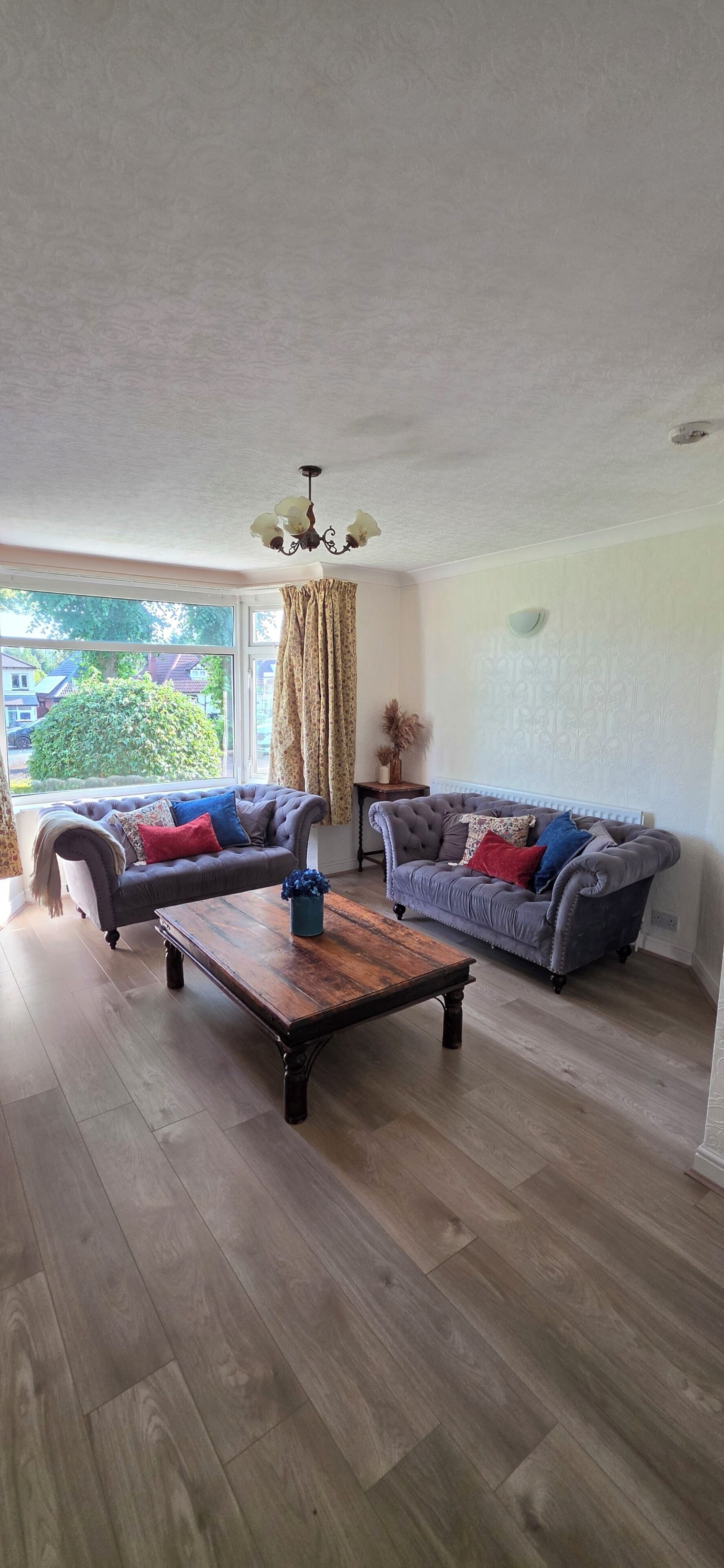 Ein geräumiges Wohnzimmer mit zwei Sofas, einem Holztisch und einem Kronleuchter.