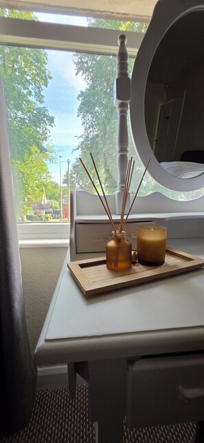 Una mesa pequeña con una vela y un difusor de aroma en una habitación con ventana.