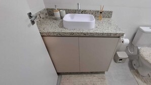 Ein Badezimmer mit Waschbecken, Toilette und einem kleinen Schrank.