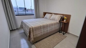 Ein Schlafzimmer mit einem Bett, einem Nachttisch, einer Vase mit Blumen und Blick durch ein Fenster.