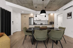 A modern kitchen with a central island, pendant lighting, and a dining area with chairs. - Secret Agent Suite | Rooftop Pool | Sleeps 6 (Québec)