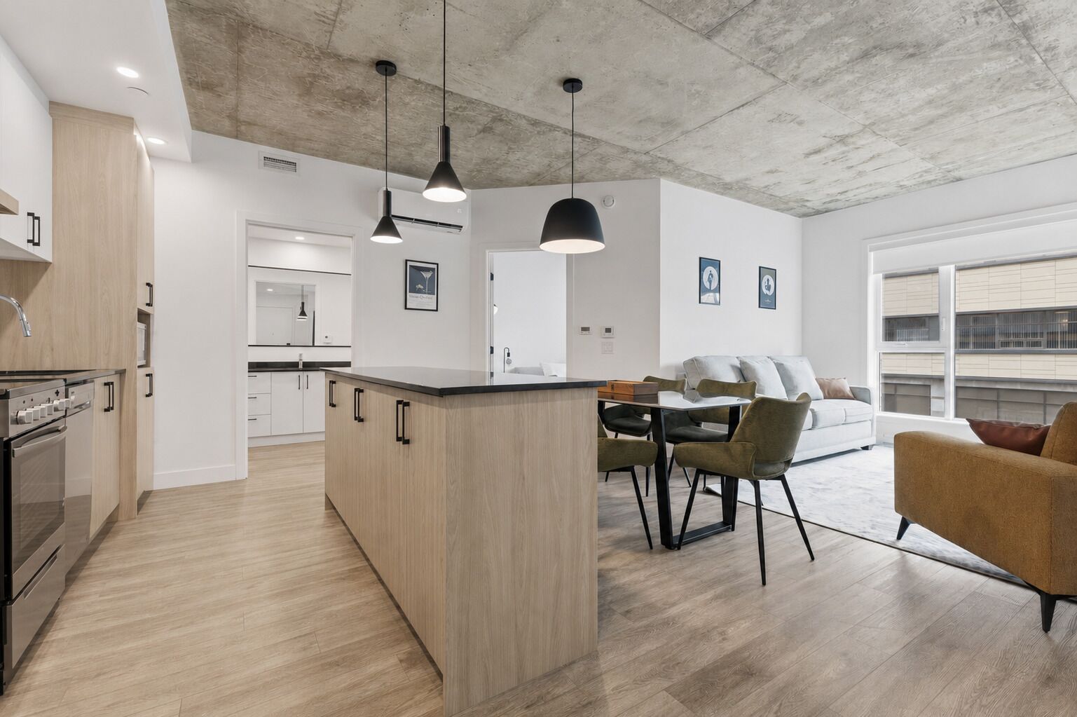 Une cuisine moderne avec un îlot central, un coin repas avec des chaises et un canapé.