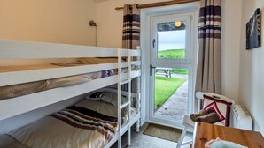 A bunk bed room with a view of a grassy area through a door. - Romantic Lyme Regis Couple's Hideaway (Bude)
