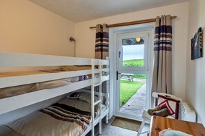 A bunk bed room with a view of a grassy area through a door. - Romantic Lyme Regis Couple's Hideaway (Bude)