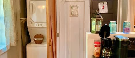 Une cuisine équipée d’un lave-linge, d’une machine à café et de différents bocaux posés sur le plan de travail.