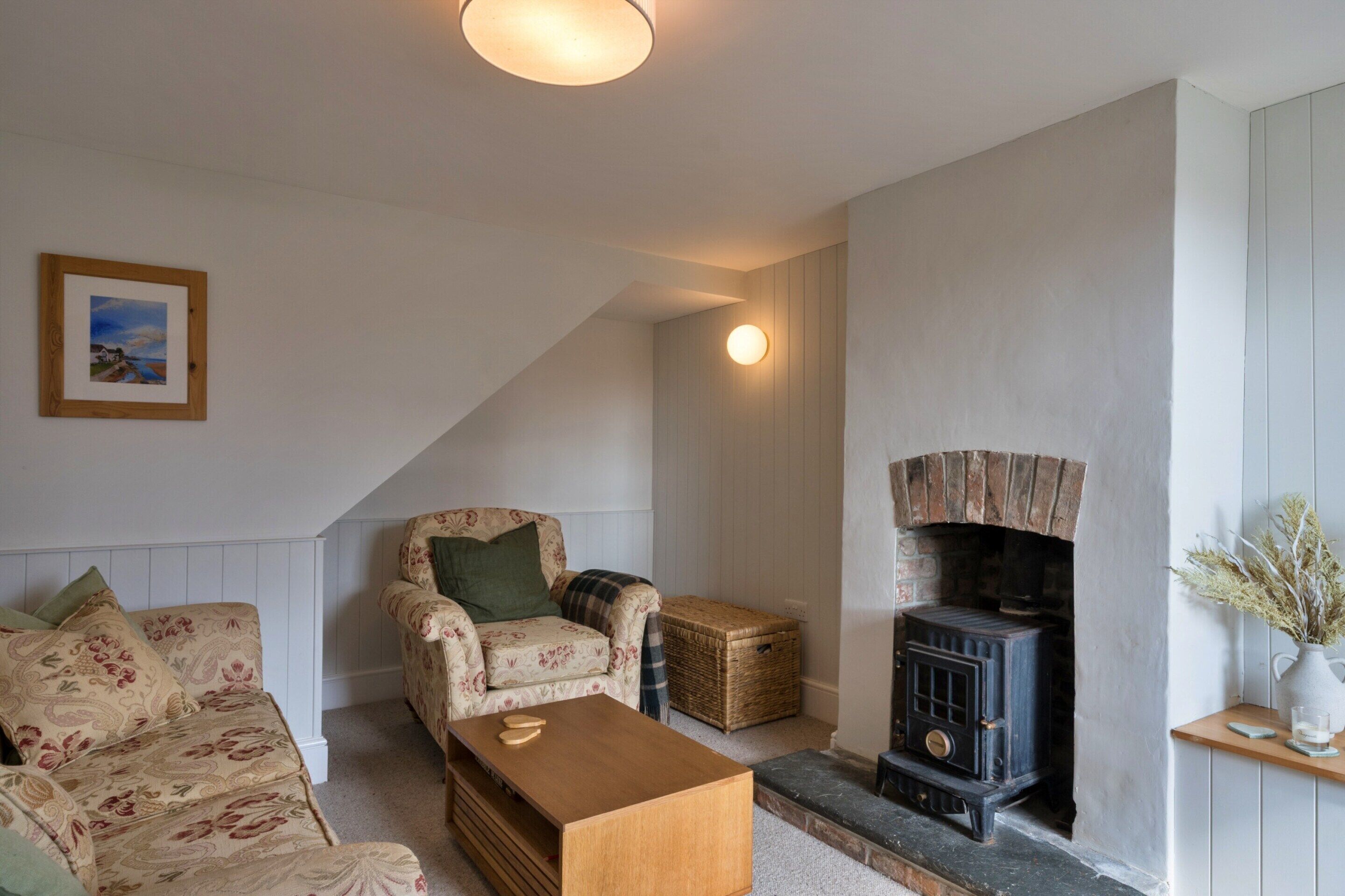 A cozy living room with a sofa, armchair, wooden coffee table, and a fireplace.