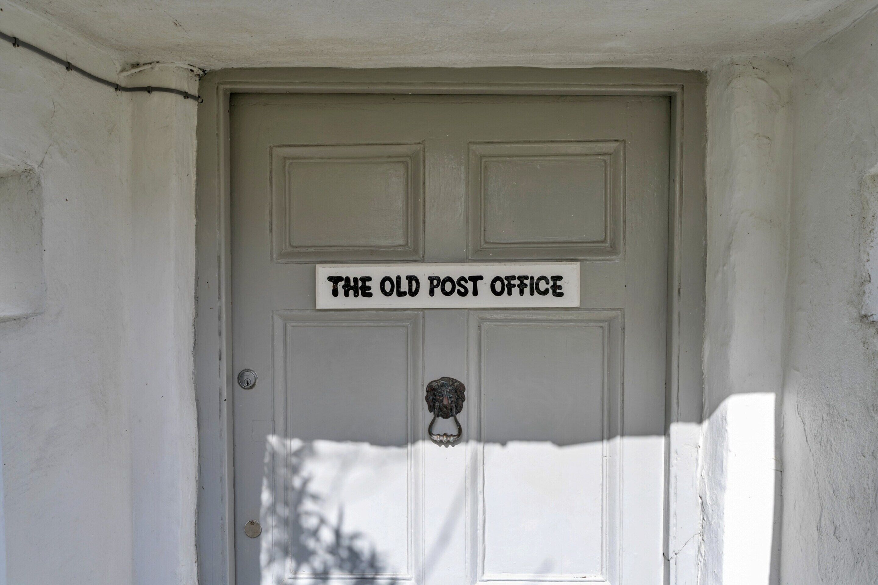 Una porta amb un cartell que diu 'THE OLD POST OFFICE'.