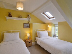 A bedroom with two beds, a skylight, a bedside lamp, and a shelf with stuffed animals. - Coastal Family House for 6 (Bude)