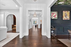 A hallway with a white reception desk, a wooden staircase, and a dark blue wall with a zebra painting. - Luxury Estate With Resort Style Pool/4BR/7Bath/Car rental/concierge upon request (Atlanta)
