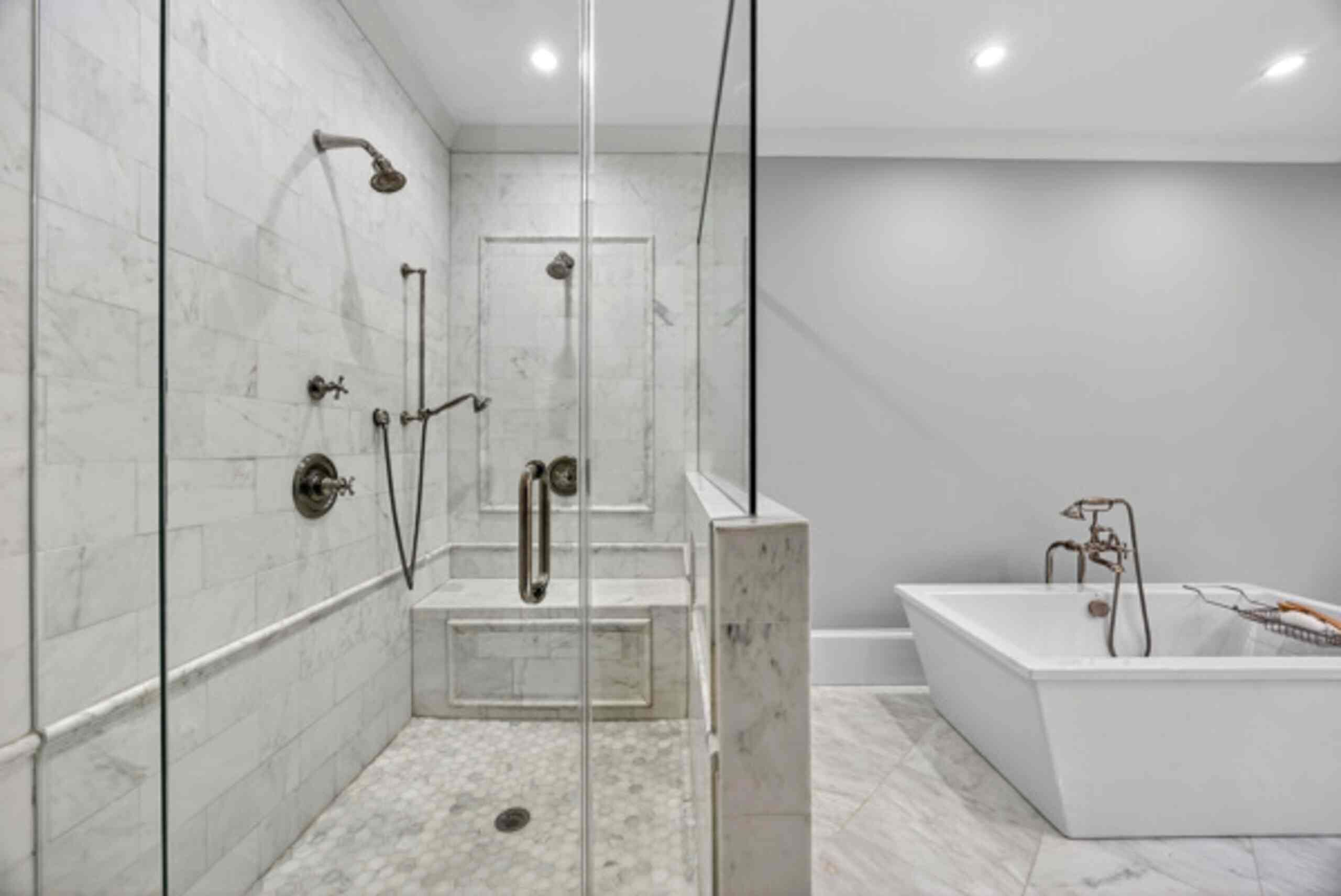 Un baño moderno con cabina de ducha de vidrio, bañera y paredes de mármol.