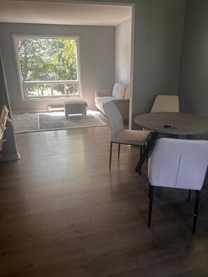 Ein Zimmer mit einem runden Tisch, zwei Stühlen, einer Bank und einem Sofa.