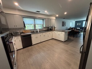 Eine moderne Küche mit Geschirrspüler, Backofen und Essbereich mit Tisch und Stühlen.