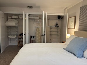 Ein Schlafzimmer mit einem Bett, einem Schrank mit Regalen und einem Sessel.