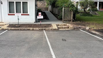 Un parking délimité par une ligne blanche, un bâtiment rouge avec une fenêtre blanche et un panneau indiquant : « 8, rue Risler, stationnement réservé aux locataires ».