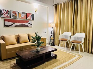 A living room with a sofa, two chairs, a coffee table, a lamp, and a plant.